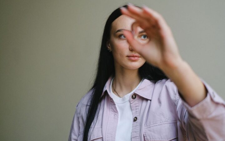 Eine Frau richtet ihren Blick an ihrer ausgestreckten Hand vorbei.